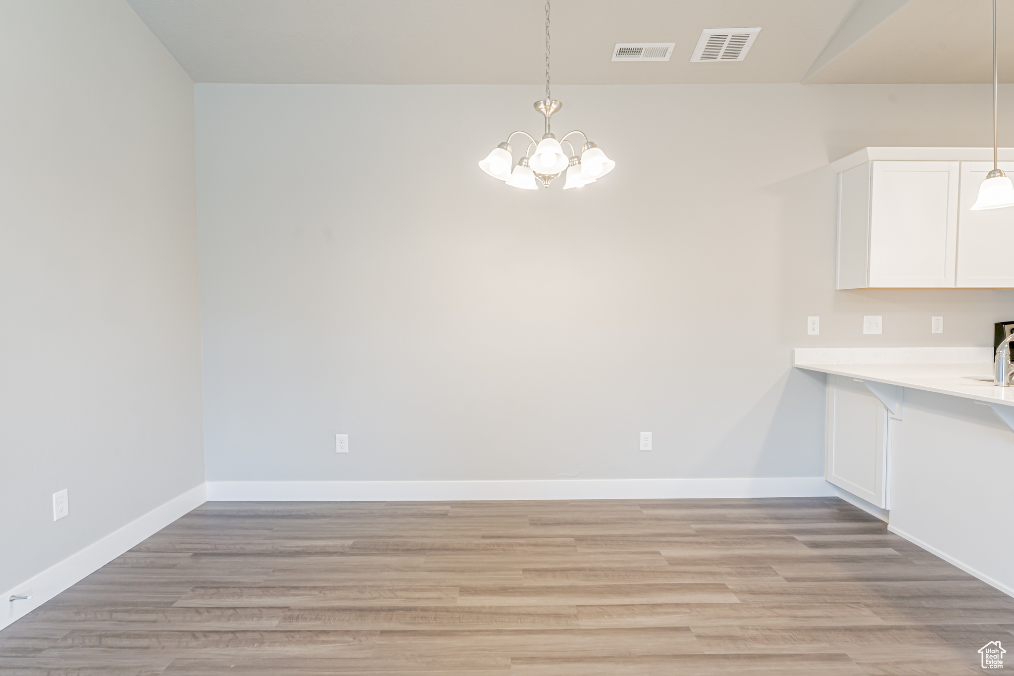 Unfurnished dining area featuring an inviting chandelier and light hardwood / wood-style floors