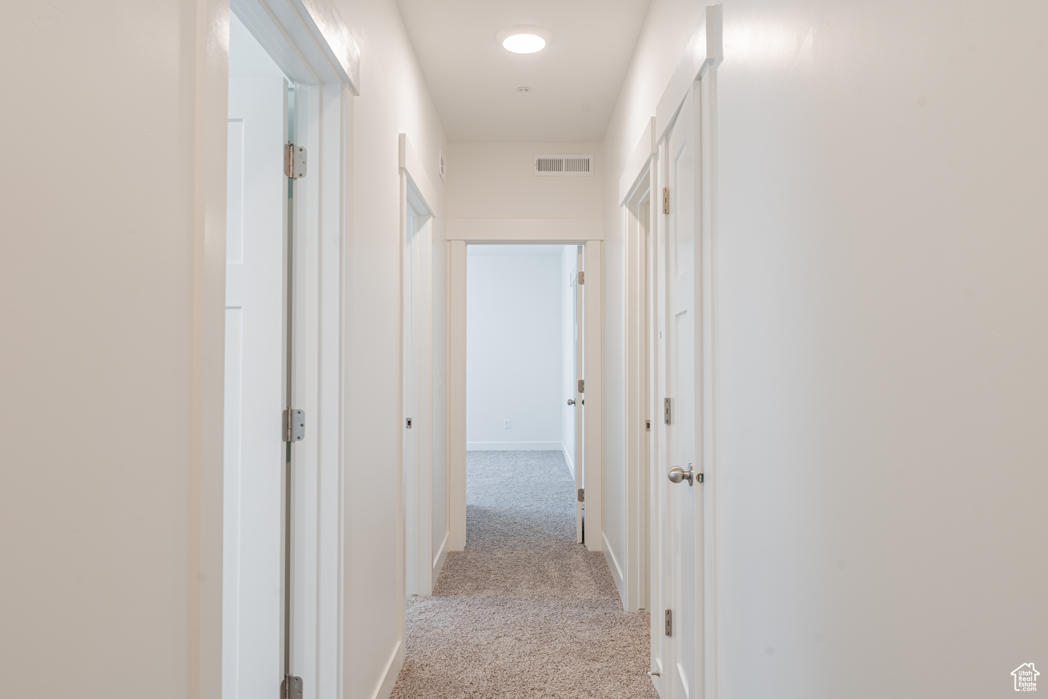 Hallway featuring light colored carpet