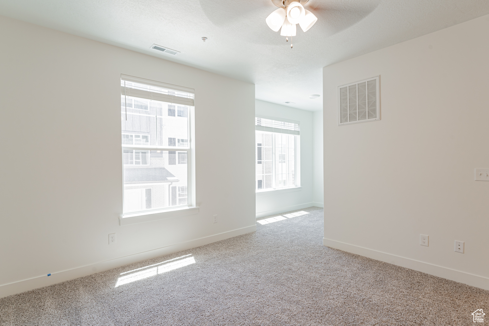 Empty room with light colored carpet and ceiling fan