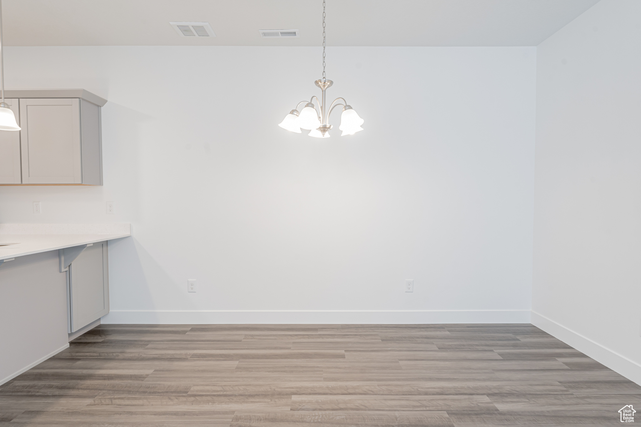 Unfurnished dining area with light hardwood / wood-style flooring and a notable chandelier