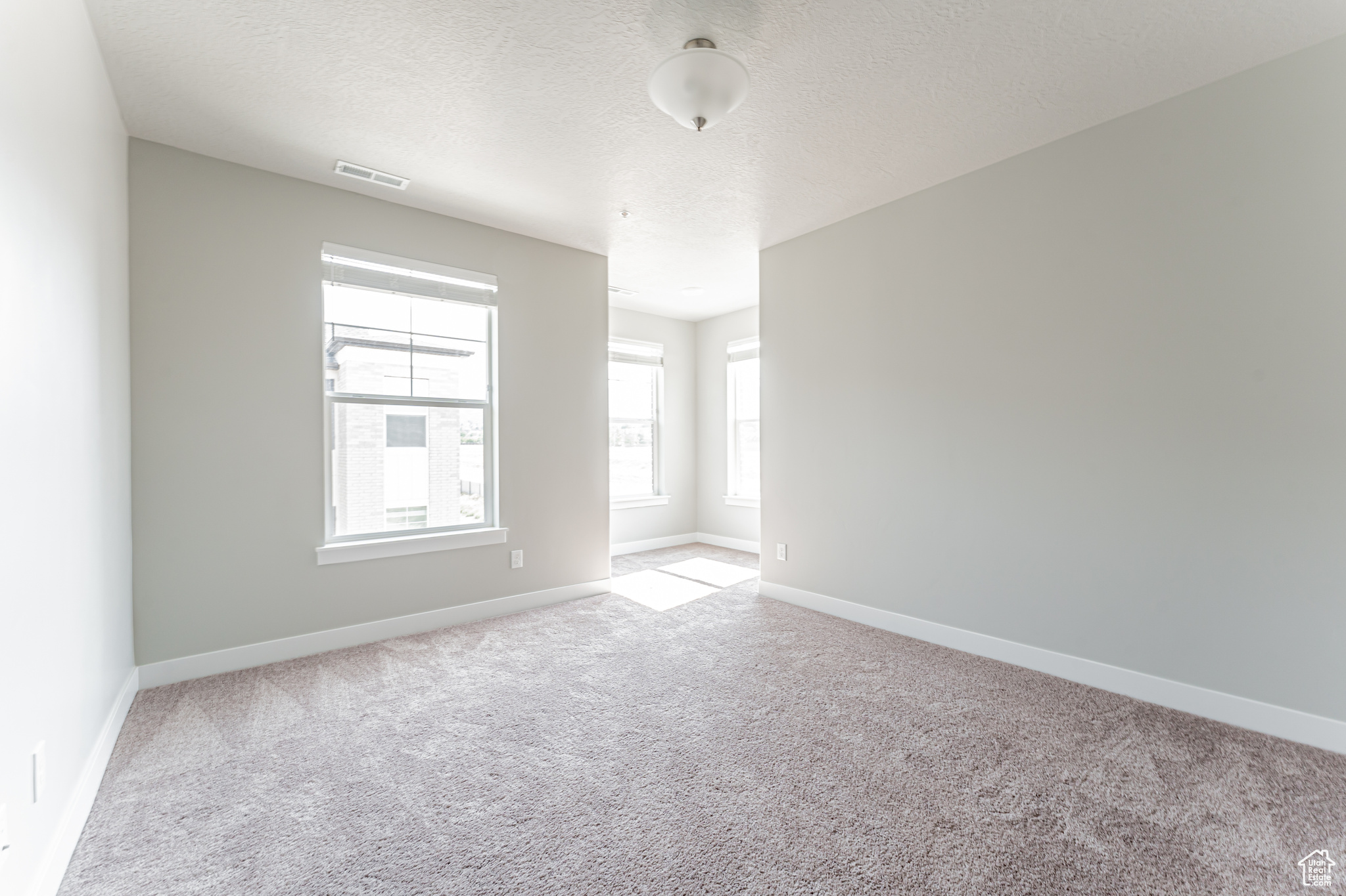 Empty room featuring carpet flooring and a textured ceiling