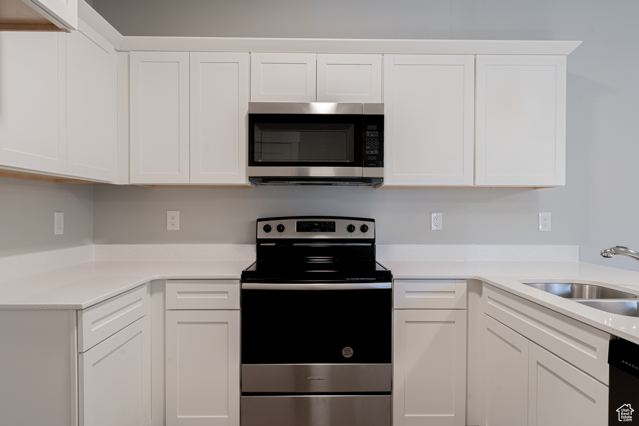 Kitchen with appliances with stainless steel finishes, sink, and white cabinetry