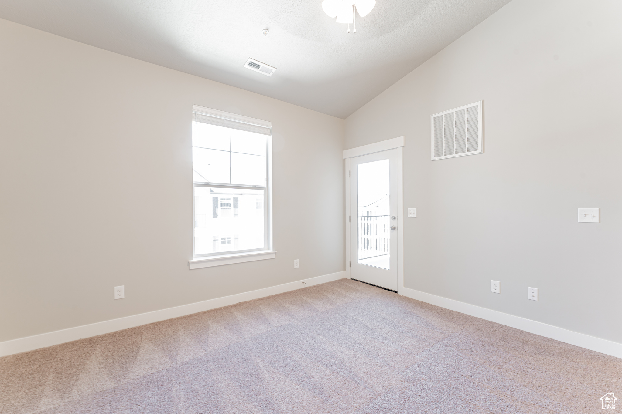 Empty room featuring ceiling fan, lofted ceiling, and light colored carpet