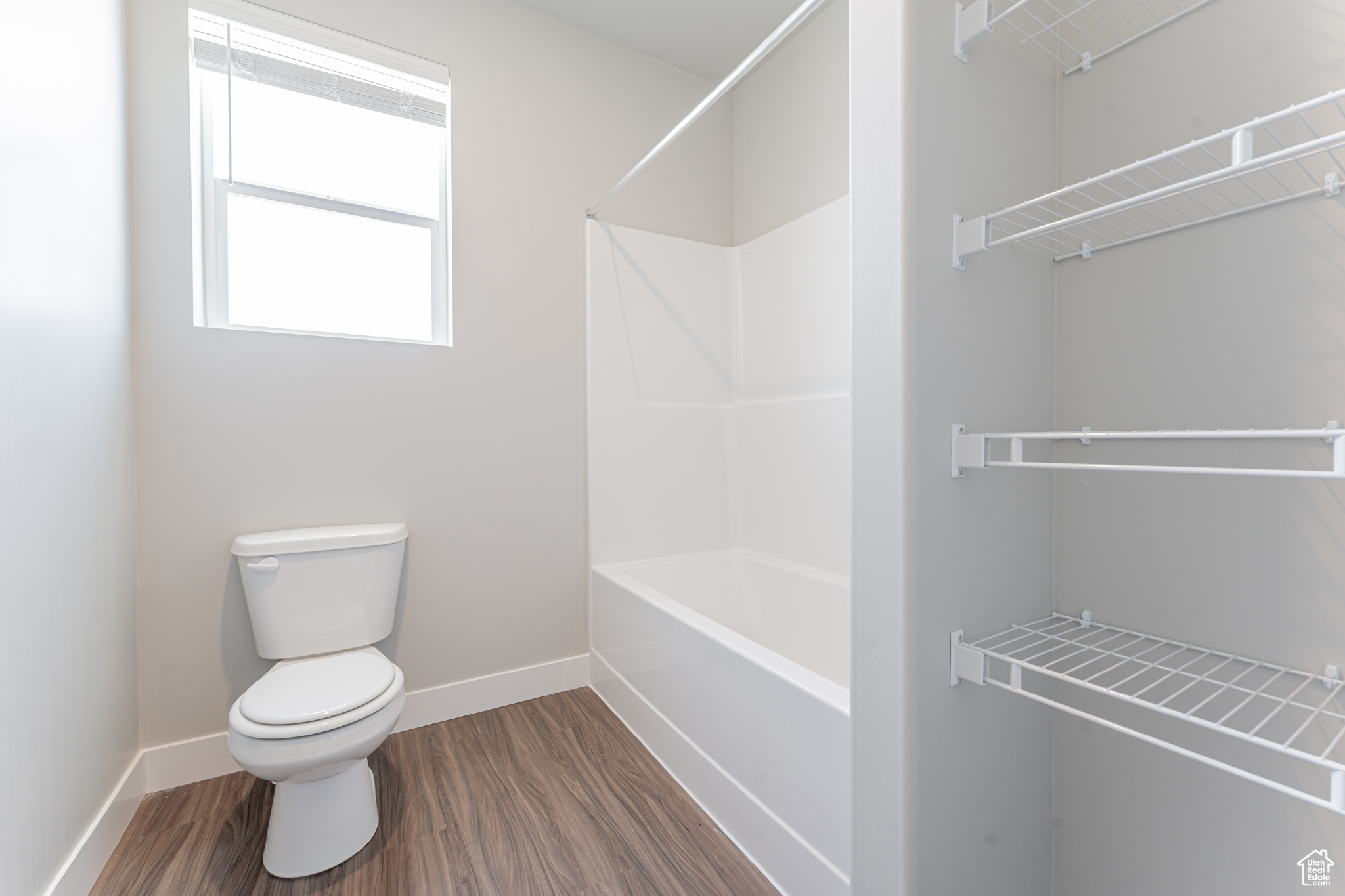 Bathroom featuring hardwood / wood-style floors, shower / bathtub combination, and toilet