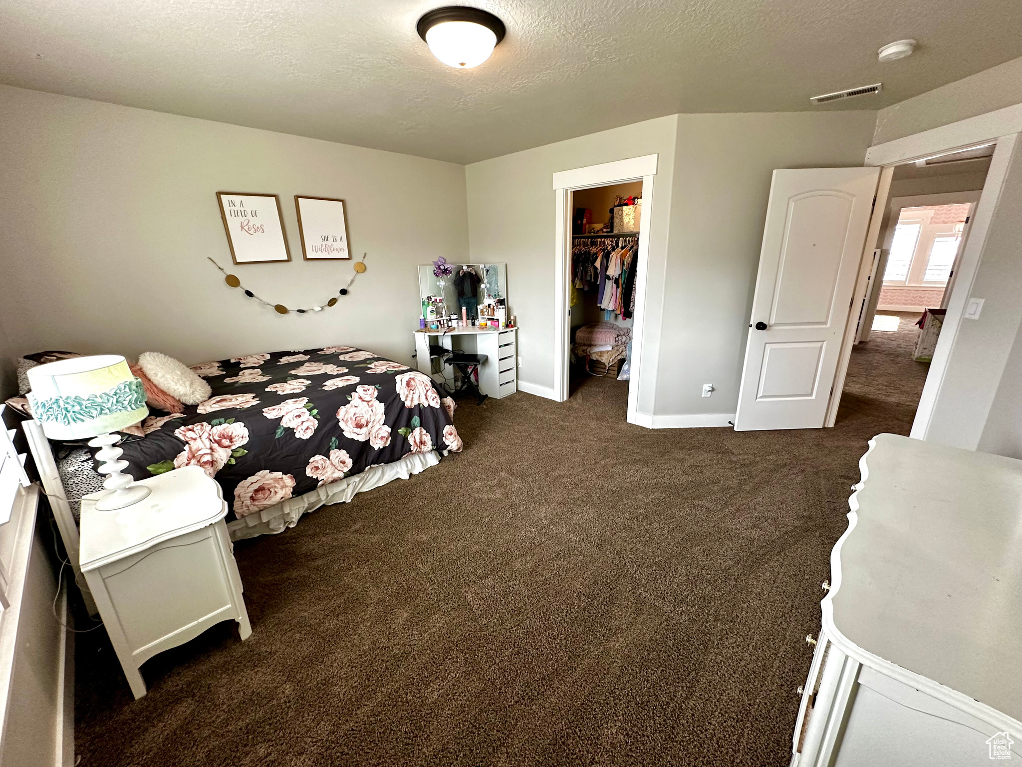 Carpeted bedroom featuring a walk in closet, a textured ceiling, and a closet