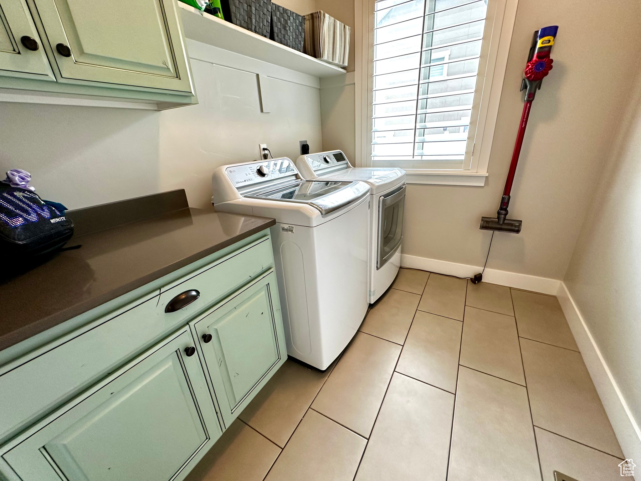 Laundry area with light tile floors, cabinets, hookup for an electric dryer, and independent washer and dryer