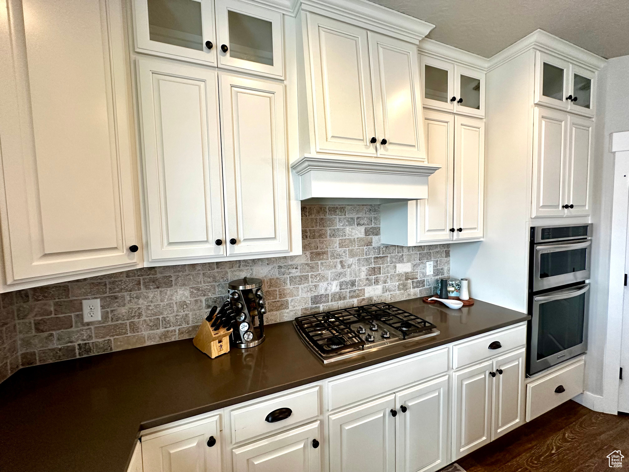 Kitchen with white cabinets, dark hardwood / wood-style floors, appliances with stainless steel finishes, and backsplash