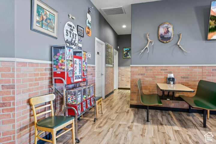 Living area with brick wall and light hardwood / wood-style floors