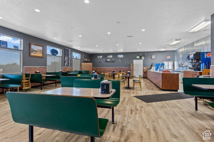 Game room with light hardwood / wood-style floors, bar area, and a wealth of natural light