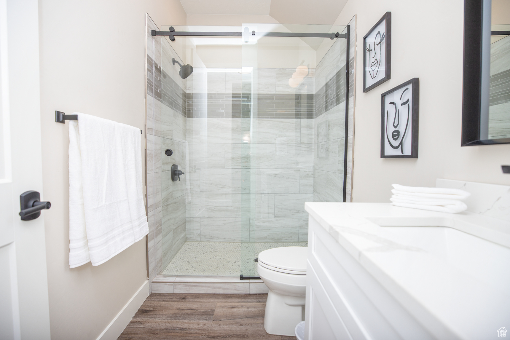 Bathroom with hardwood / wood-style floors, toilet, vanity, and walk in shower