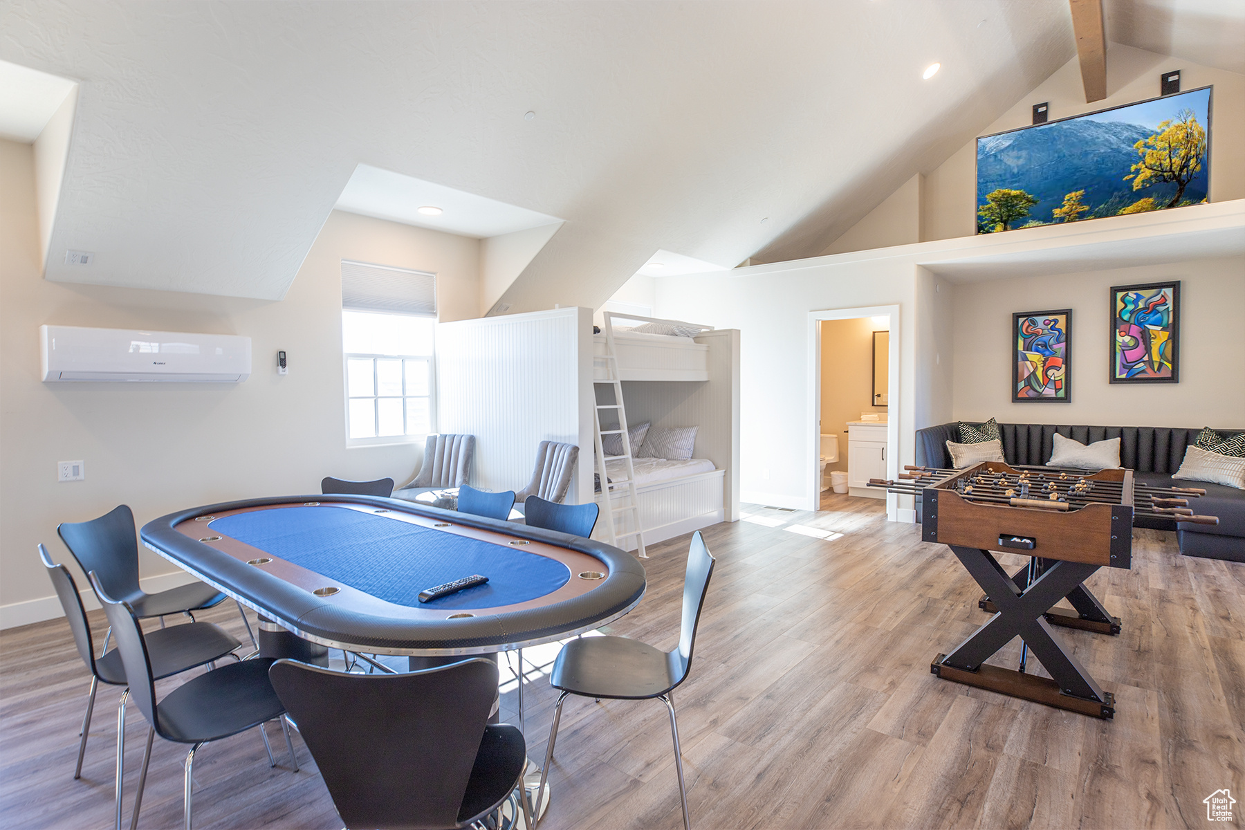 Recreation room featuring a wall mounted air conditioner, beamed ceiling, light hardwood / wood-style floors, and high vaulted ceiling
