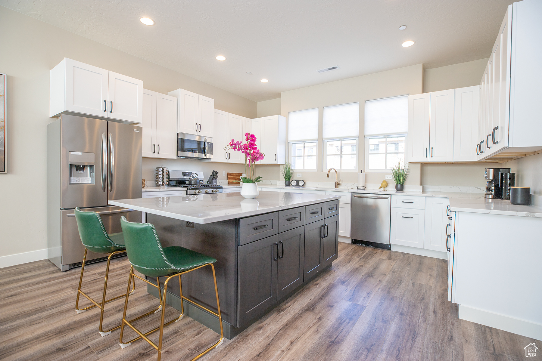 Kitchen featuring a breakfast bar, light hardwood / wood-style floors, appliances with stainless steel finishes, a kitchen island, and white cabinetry