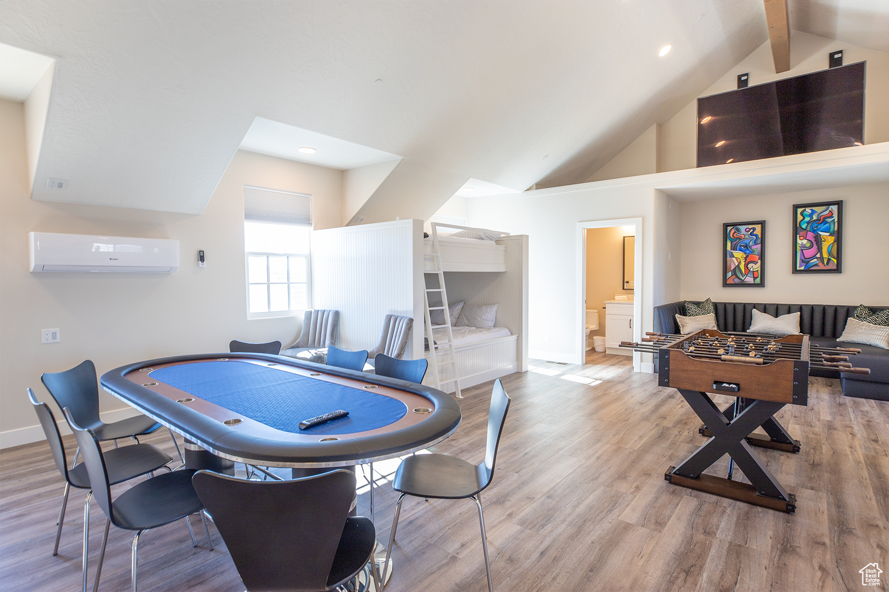 Recreation room featuring a wall mounted AC, light hardwood / wood-style floors, beamed ceiling, and high vaulted ceiling