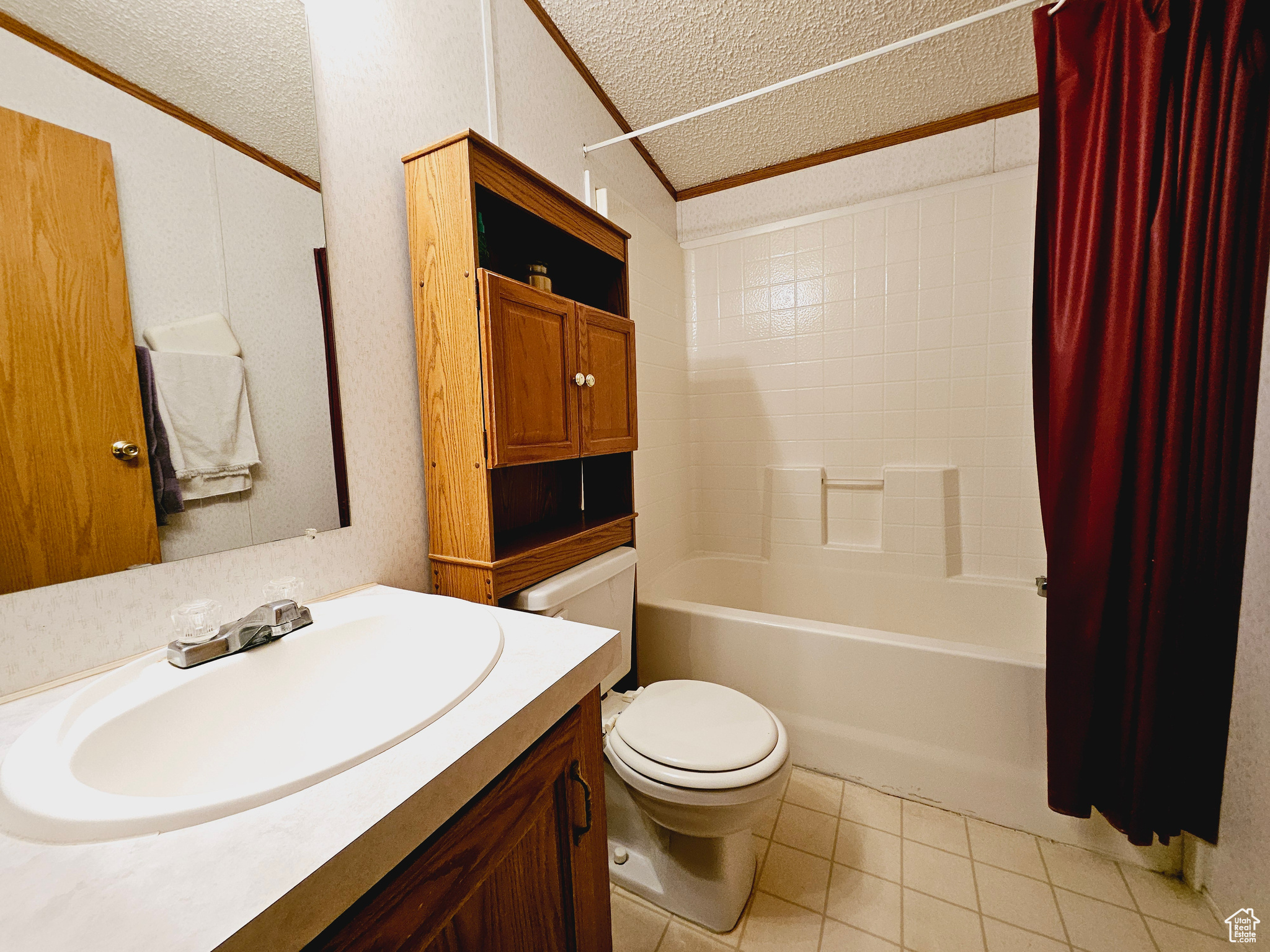 Full bathroom featuring a textured ceiling, tile floors, vanity, toilet, and shower / tub combo