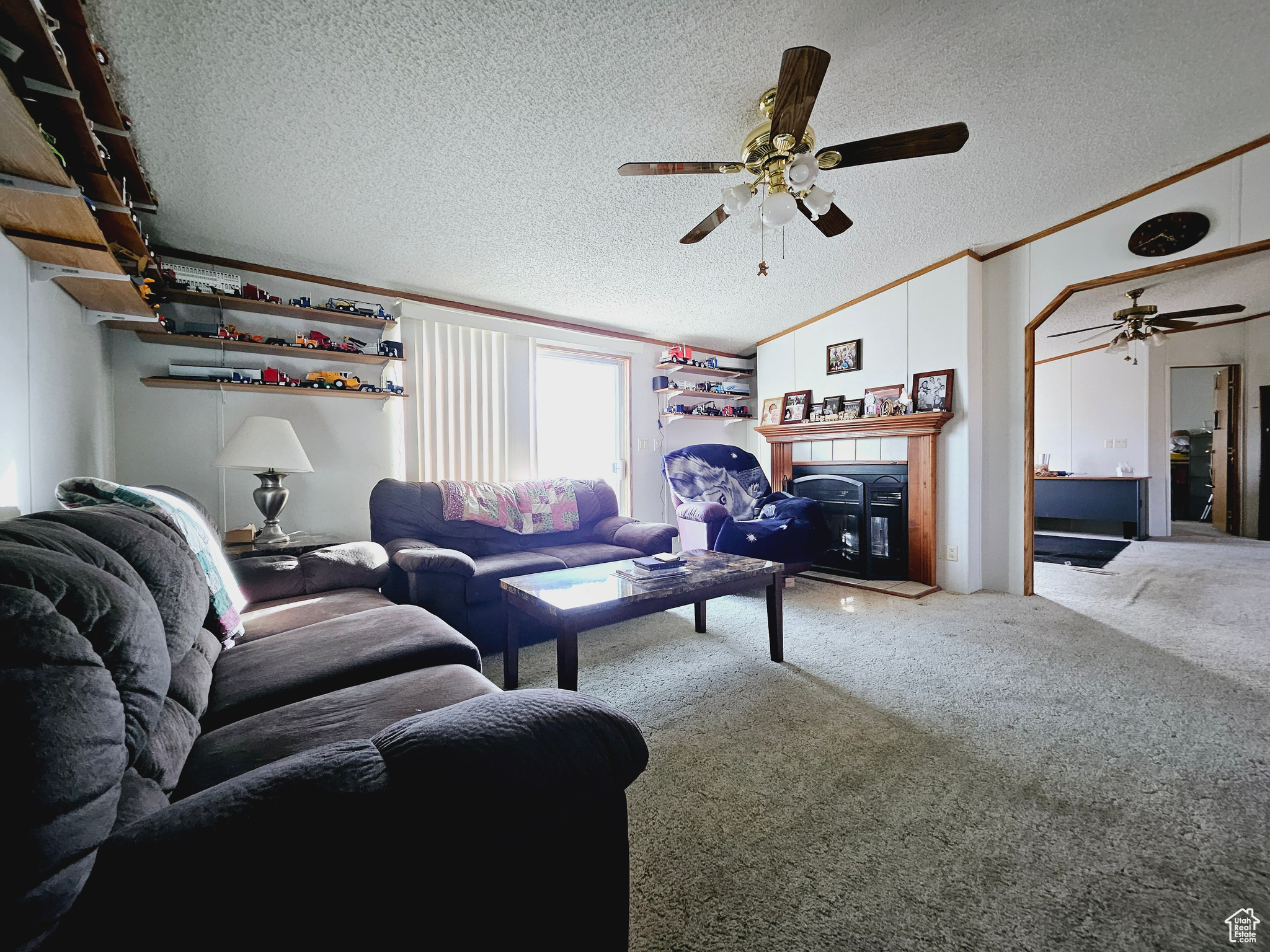 Living room with carpet flooring, a textured ceiling, ceiling fan, and lofted ceiling