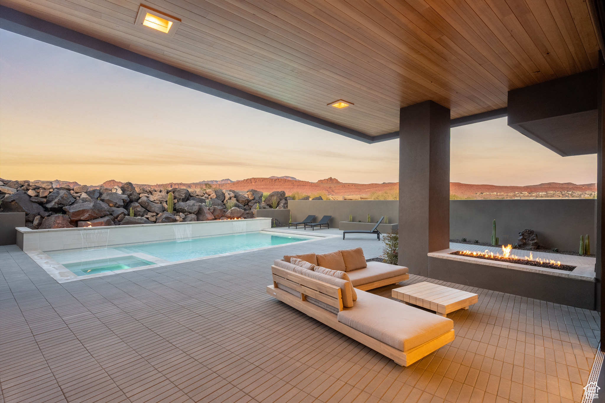 Pool at dusk featuring a mountain view and an outdoor living space with a fire pit