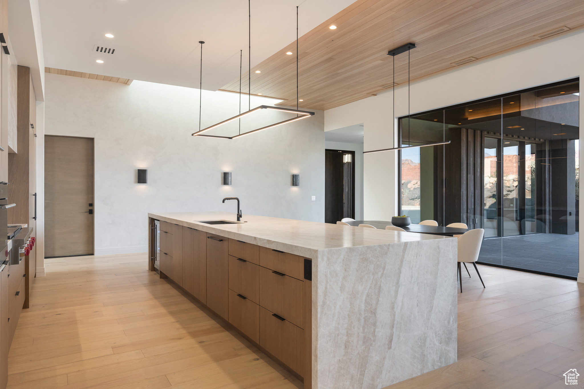 Kitchen featuring light stone countertops, sink, pendant lighting, a large island with sink, and wooden ceiling