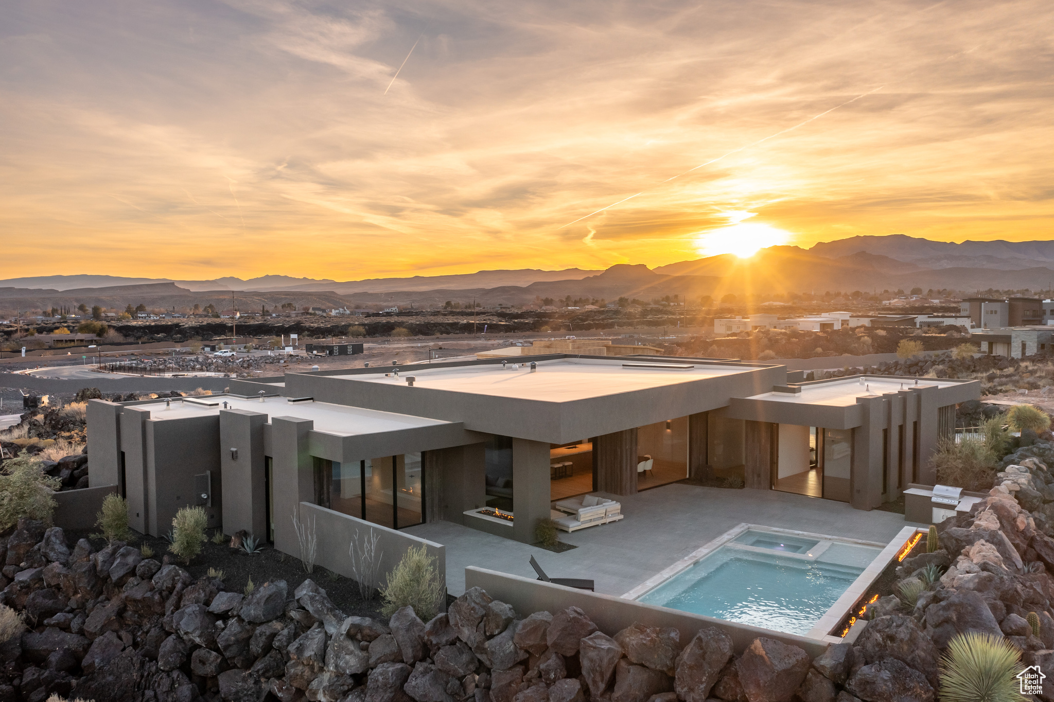 Back house at dusk featuring a mountain view, a patio area, and an in ground hot tub