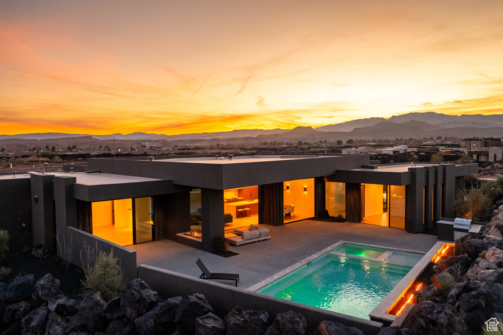 Back house at dusk with a mountain view, a patio, and a pool