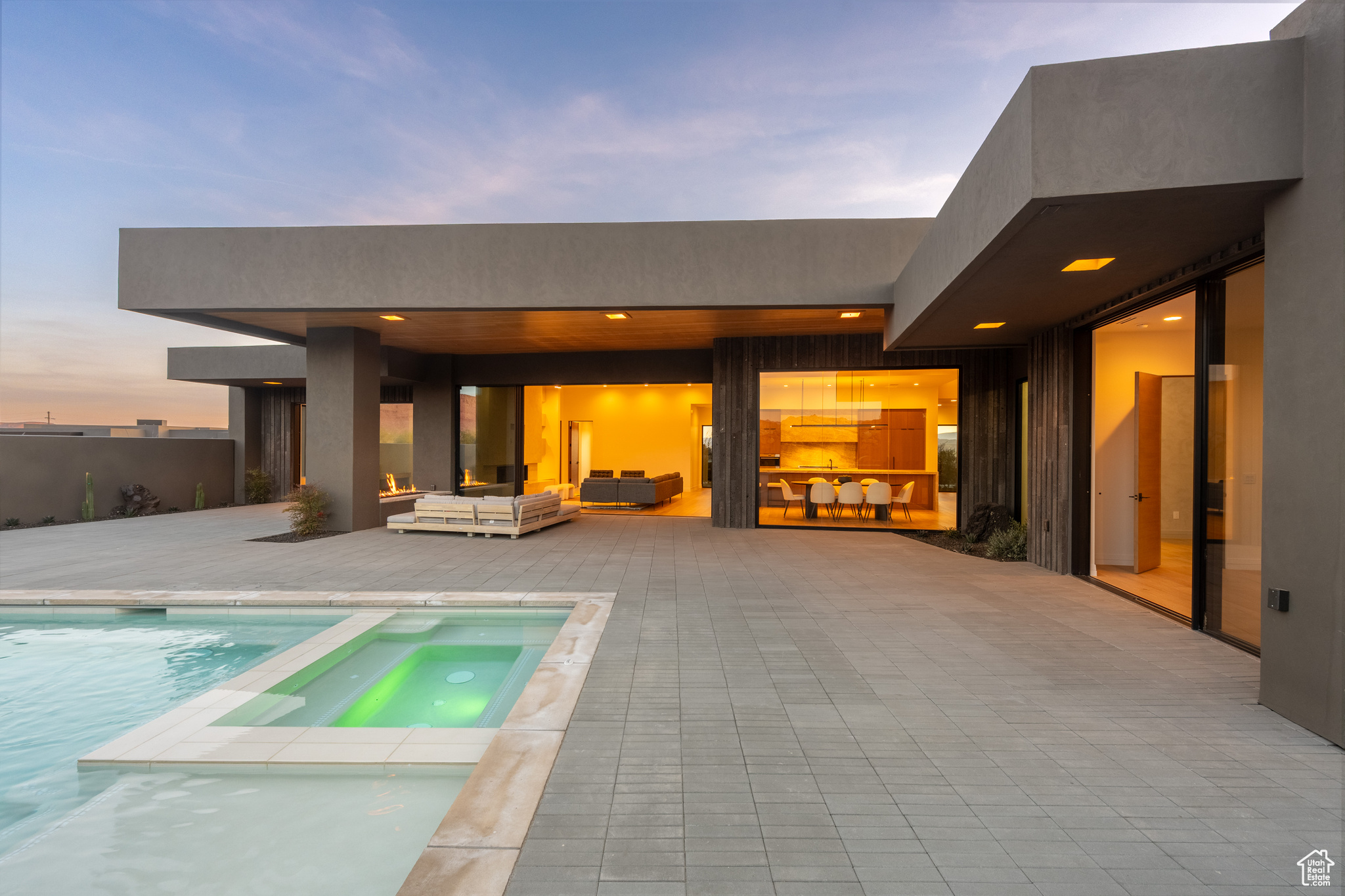 Pool at dusk with an outdoor living space, an in ground hot tub, and a patio