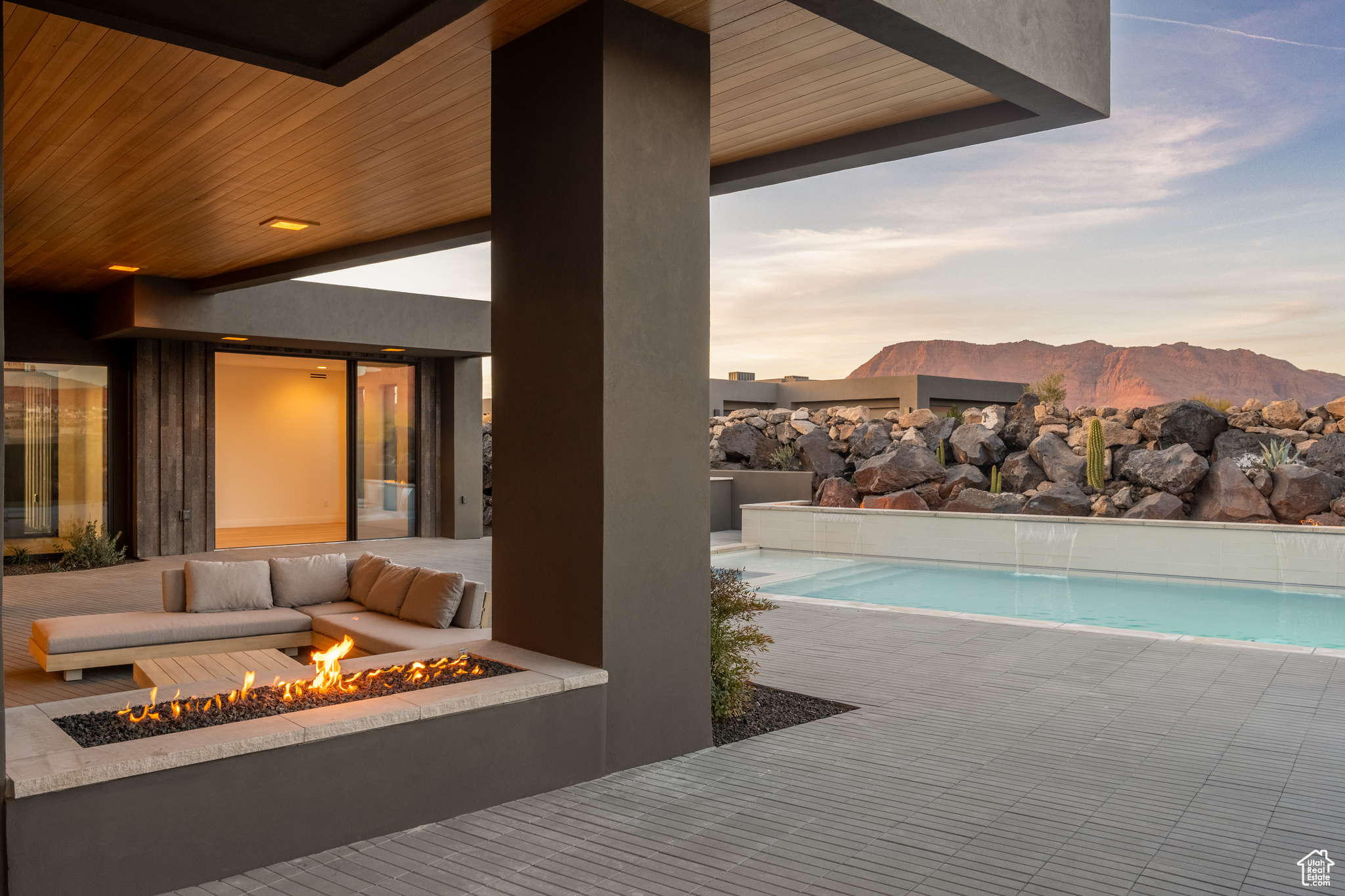 Pool at dusk featuring a mountain view, a patio, and an outdoor living space with a fire pit