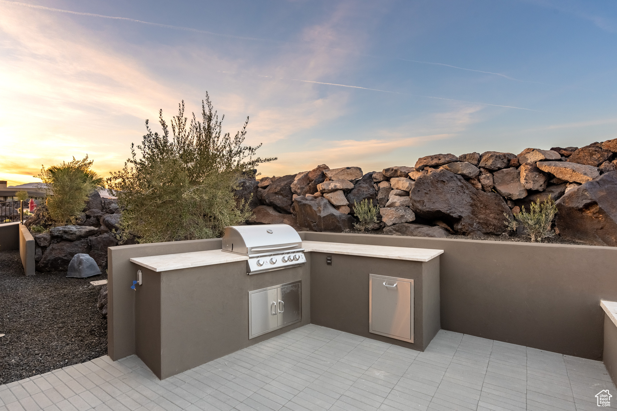 Patio terrace at dusk with an outdoor kitchen and area for grilling