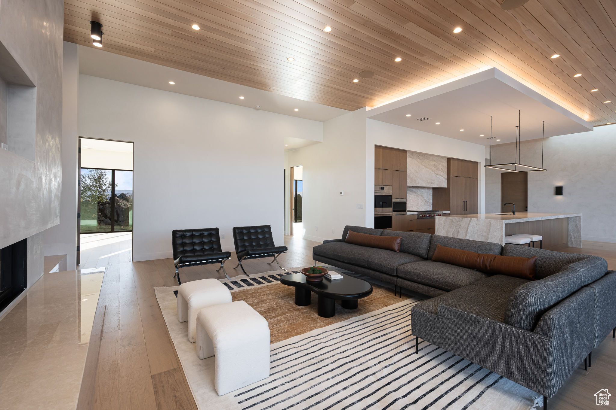 Living room with a high end fireplace, sink, light hardwood / wood-style flooring, and wood ceiling