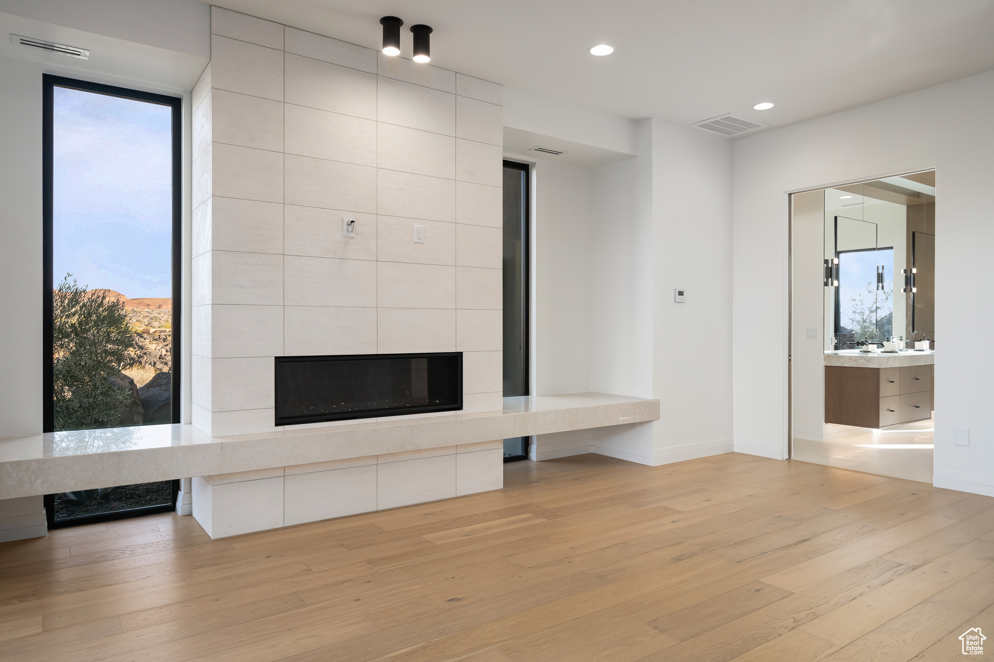 Unfurnished living room with a tiled fireplace and light hardwood / wood-style flooring