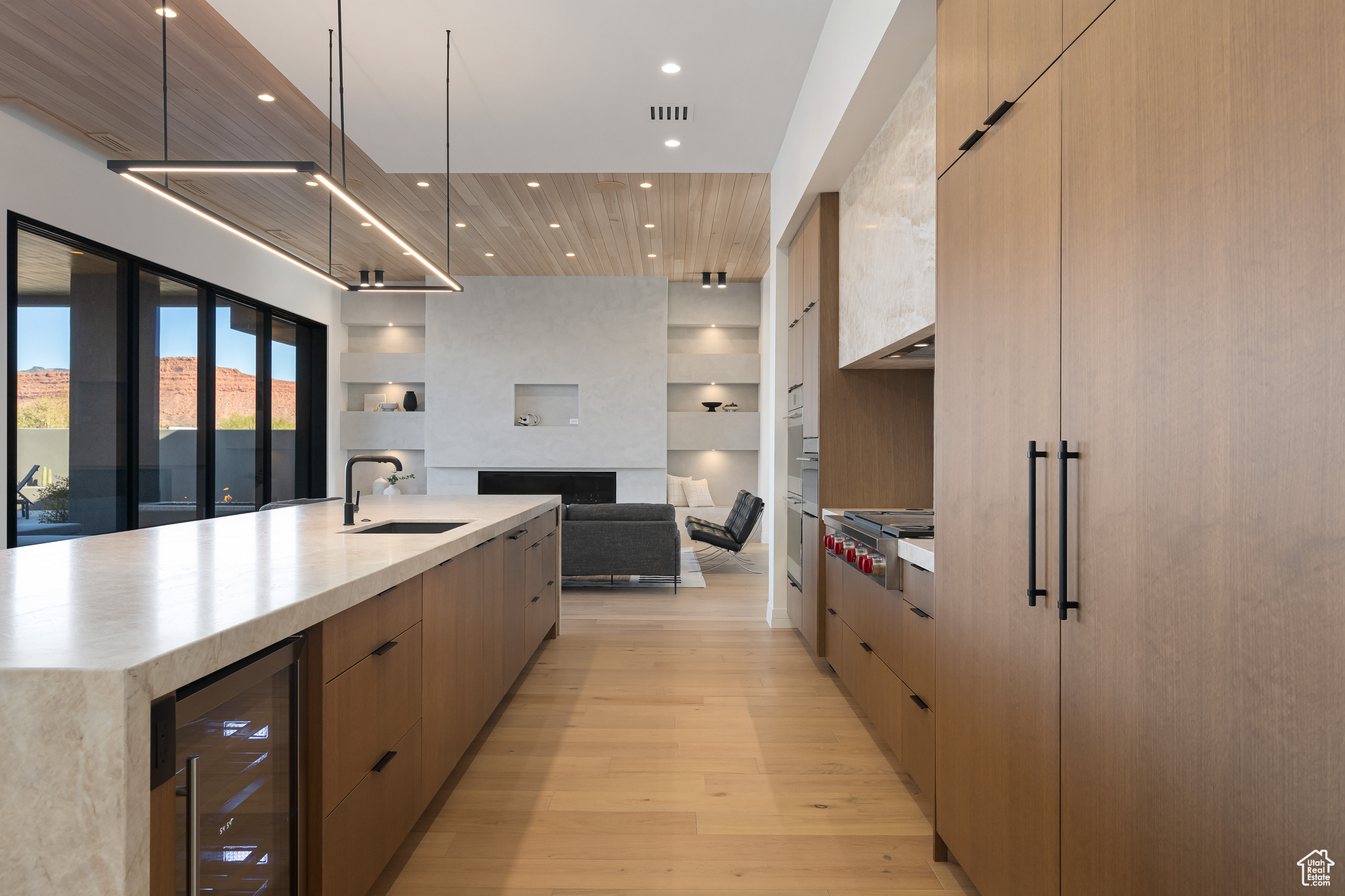 Kitchen featuring light brown cabinets, a spacious island, sink, and beverage cooler