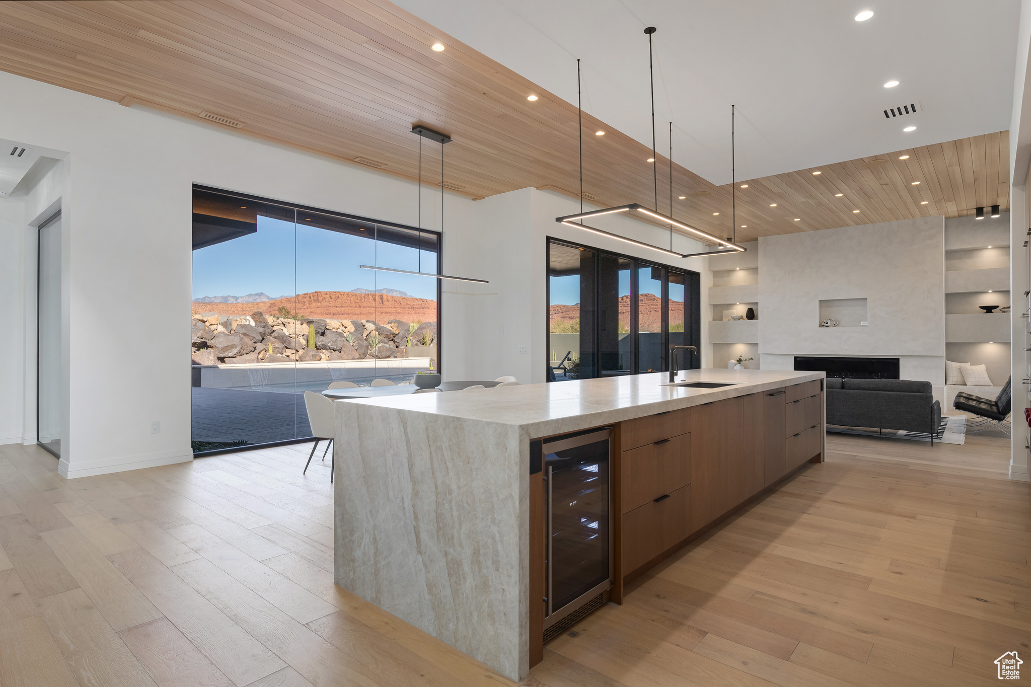 Kitchen with beverage cooler, sink, a large island with sink, wooden ceiling, and a mountain view