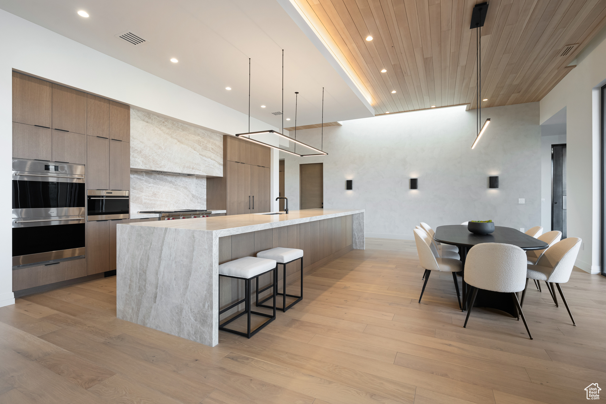 Kitchen with decorative light fixtures, wooden ceiling, sink, and a large island with sink