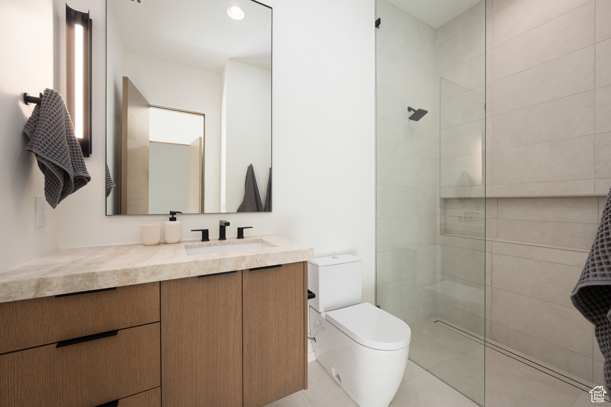 Bathroom with a tile shower, vanity, and toilet