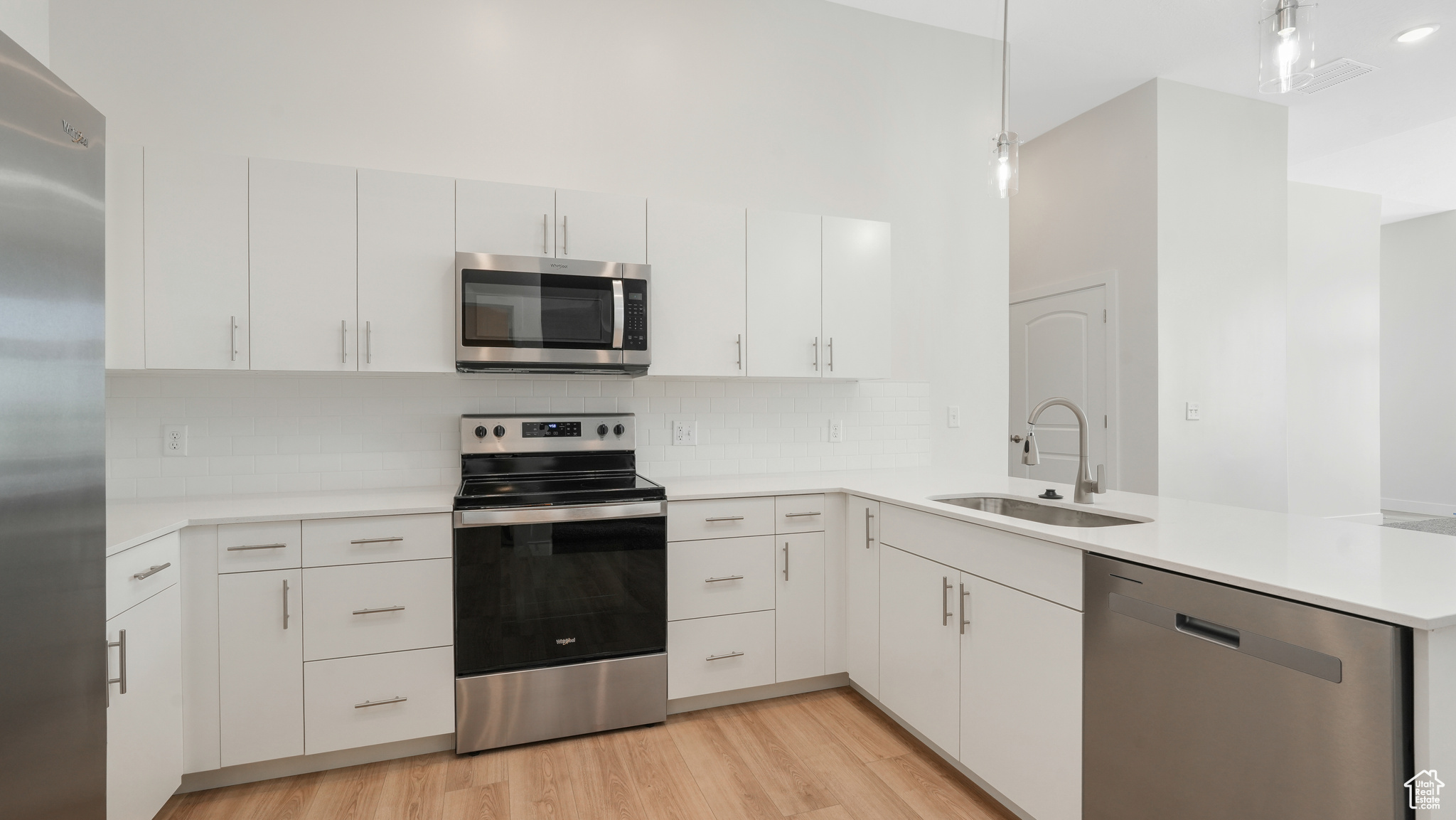Bright modern kitchen with stainless steel appliances, quartz counters, and tile backsplash. Fridge Included!