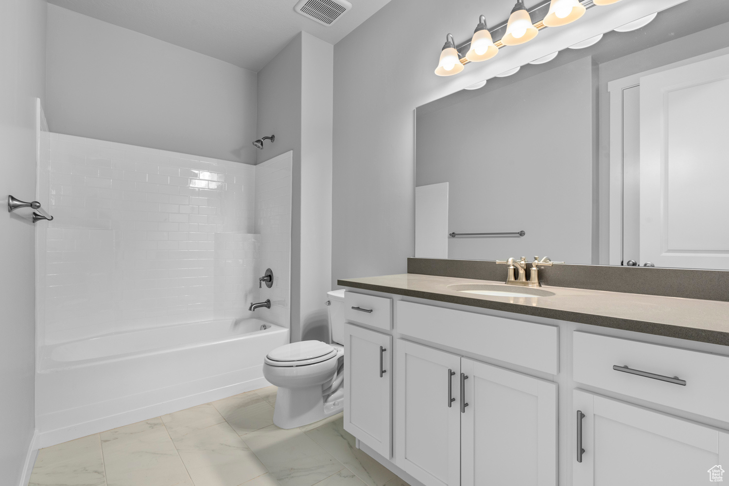 Full bathroom featuring tile flooring, toilet, vanity, and washtub / shower combination