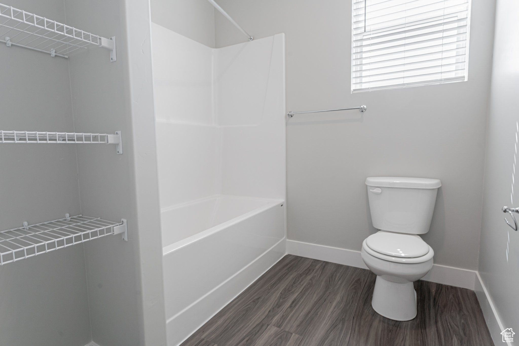 Bathroom with shower / bathtub combination, wood-type flooring, and toilet