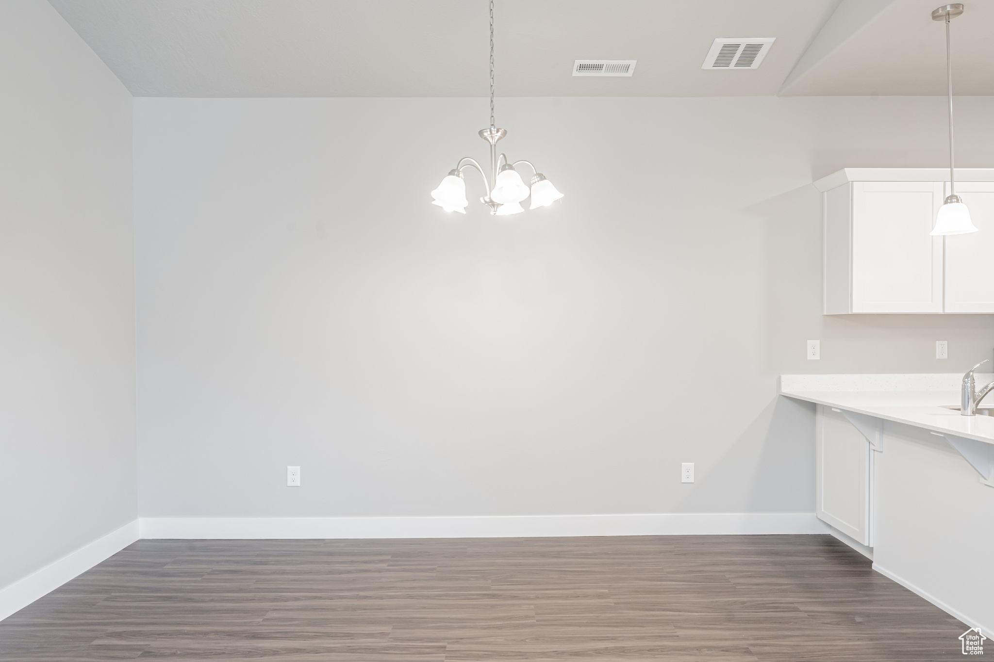 Unfurnished dining area with an inviting chandelier and hardwood / wood-style floors