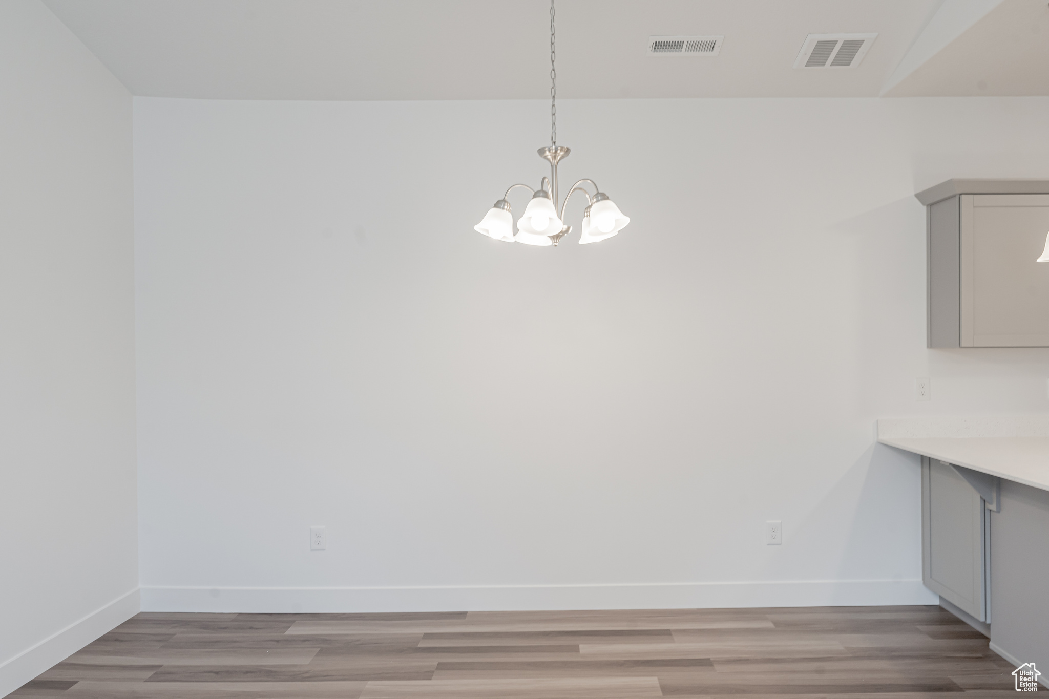 Unfurnished dining area with a notable chandelier and light hardwood / wood-style floors