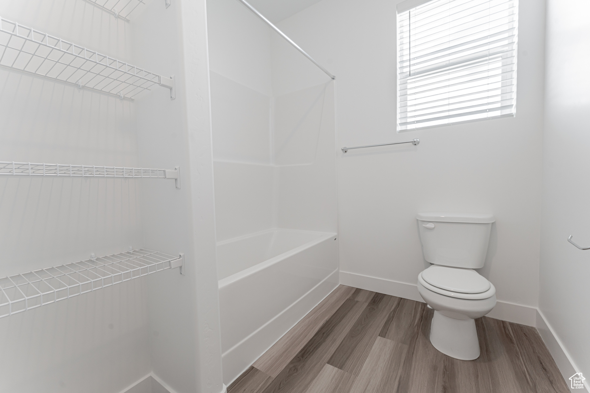 Bathroom featuring shower / tub combination, hardwood / wood-style flooring, and toilet