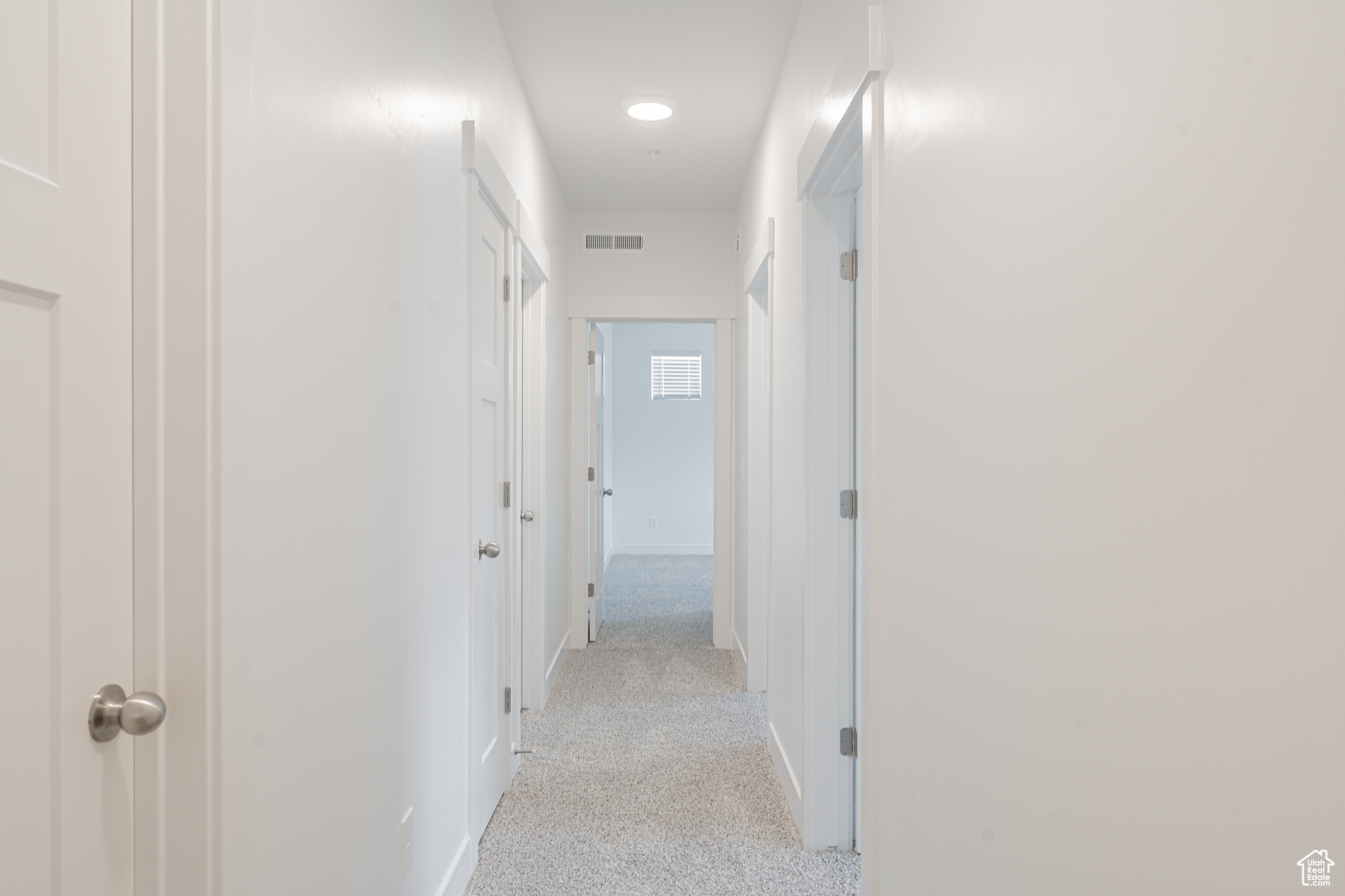 Hallway featuring light colored carpet