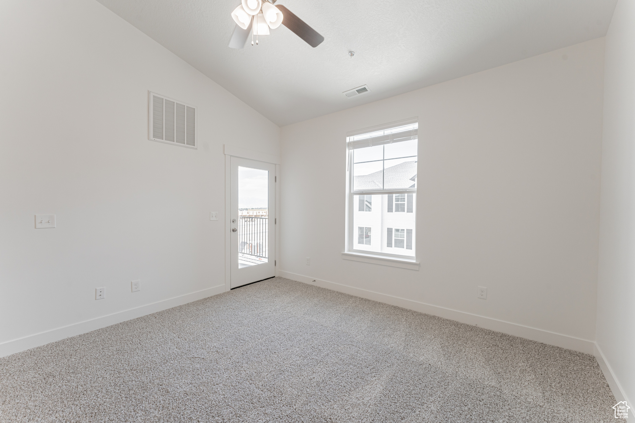 Carpeted empty room with ceiling fan and vaulted ceiling