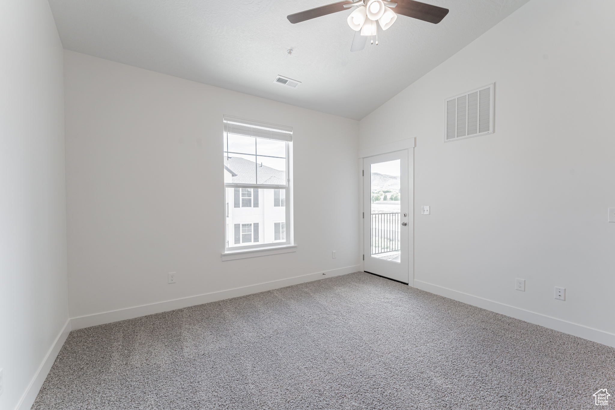 Unfurnished room with plenty of natural light, carpet, and lofted ceiling