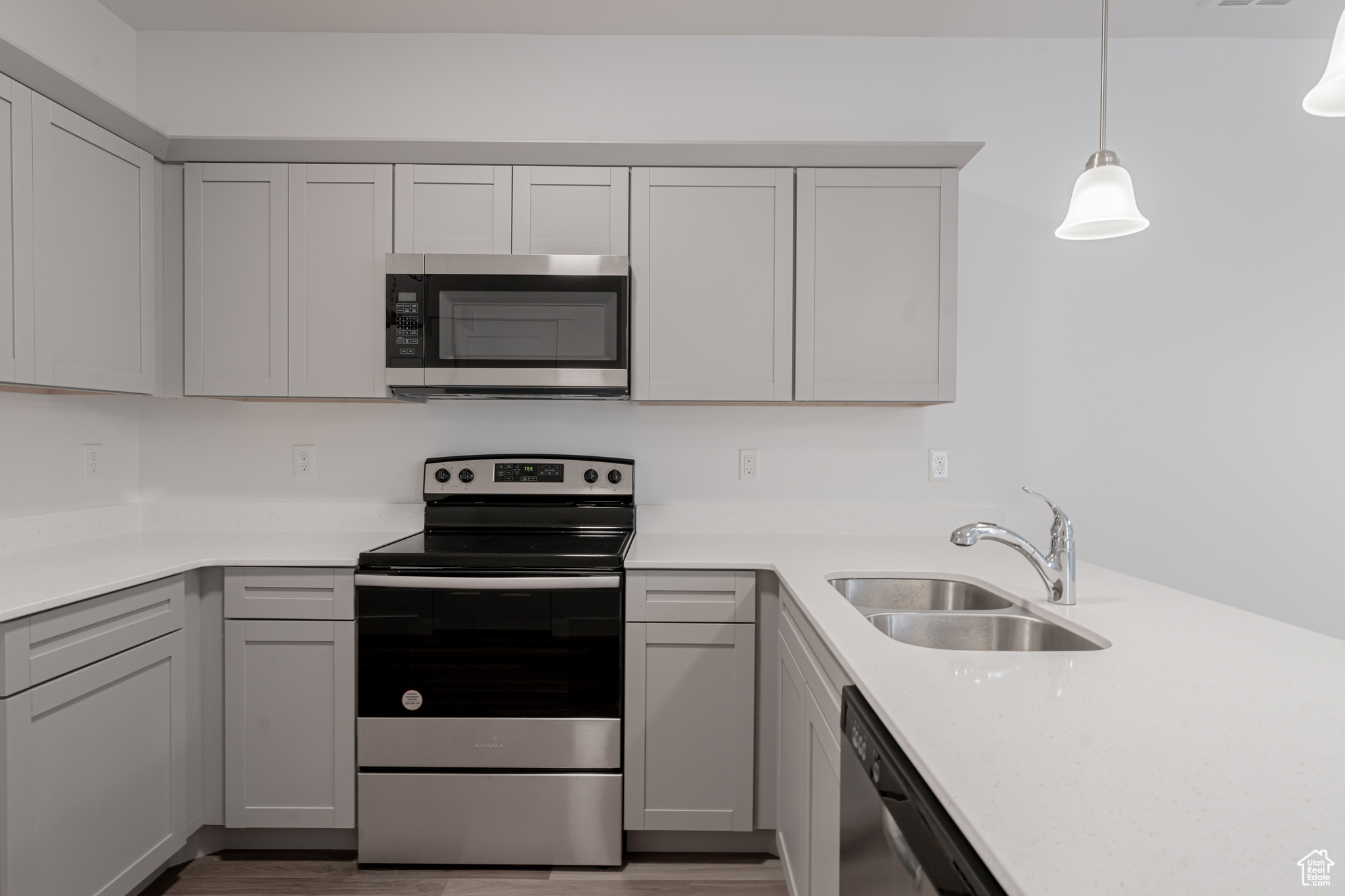 Kitchen with hanging light fixtures, sink, light hardwood / wood-style flooring, and stainless steel appliances