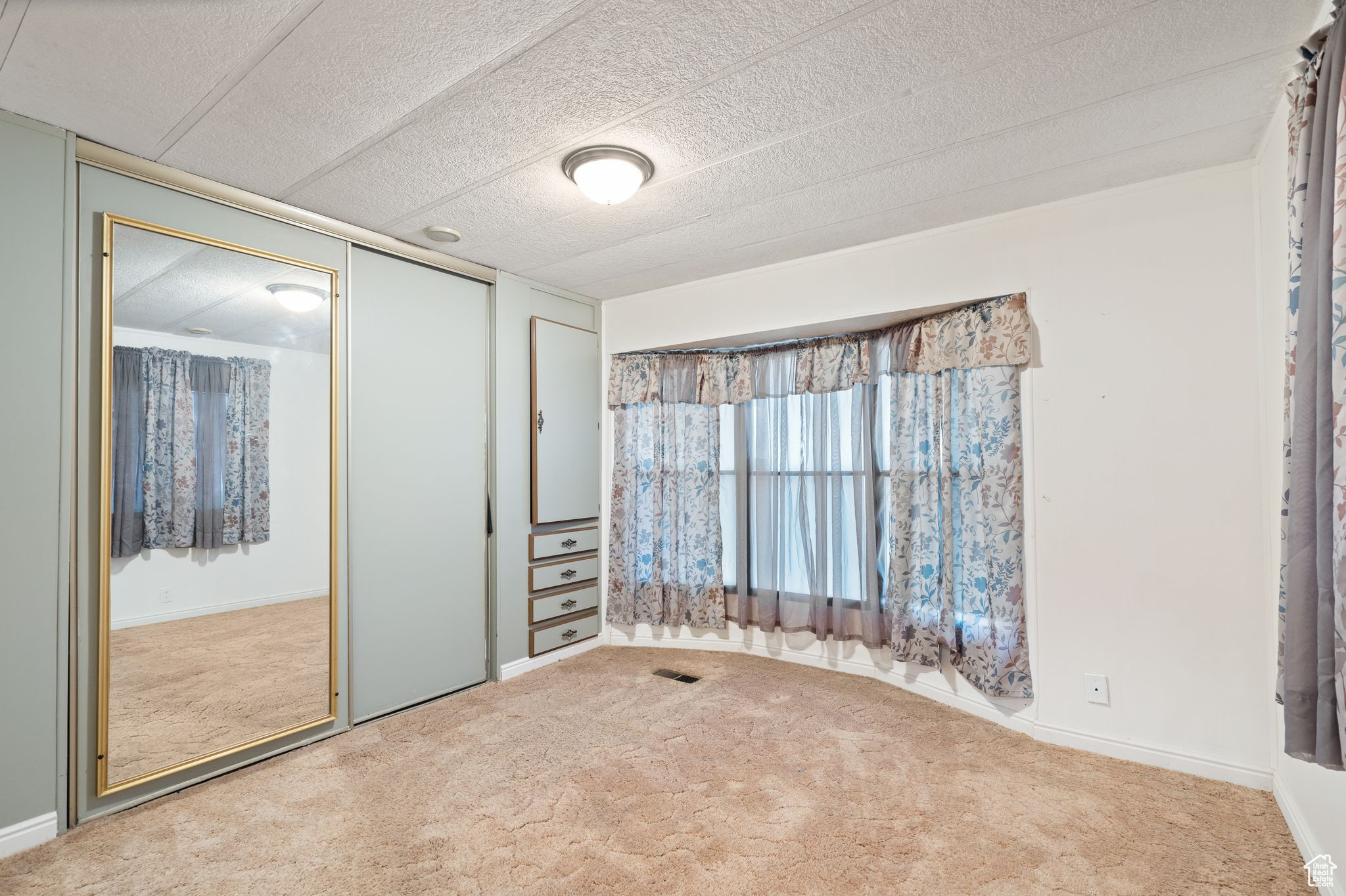Unfurnished room featuring light colored carpet and a textured ceiling