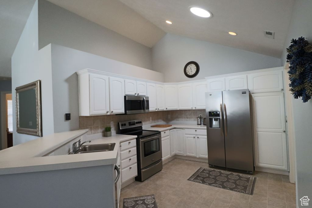 Kitchen featuring backsplash, white cabinetry, sink, light tile floors, and appliances with stainless steel finishes