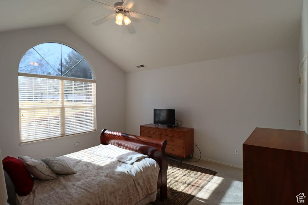 Bedroom featuring ceiling fan, light colored carpet, and lofted ceiling