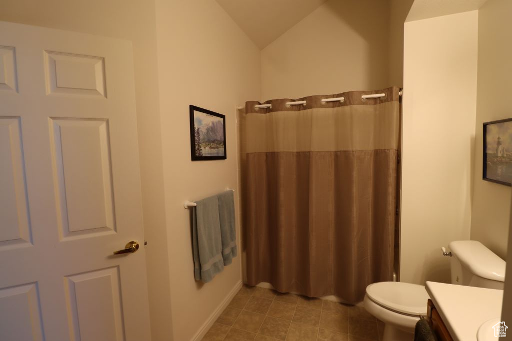 Bathroom with vanity, toilet, vaulted ceiling, and tile flooring