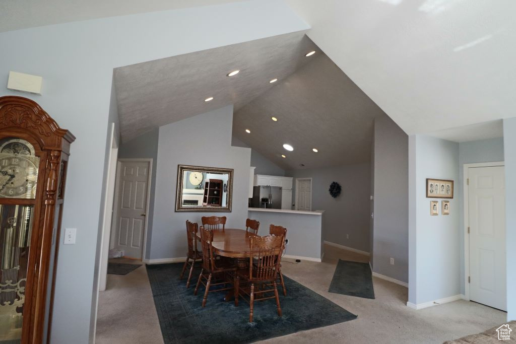 Carpeted dining room featuring lofted ceiling