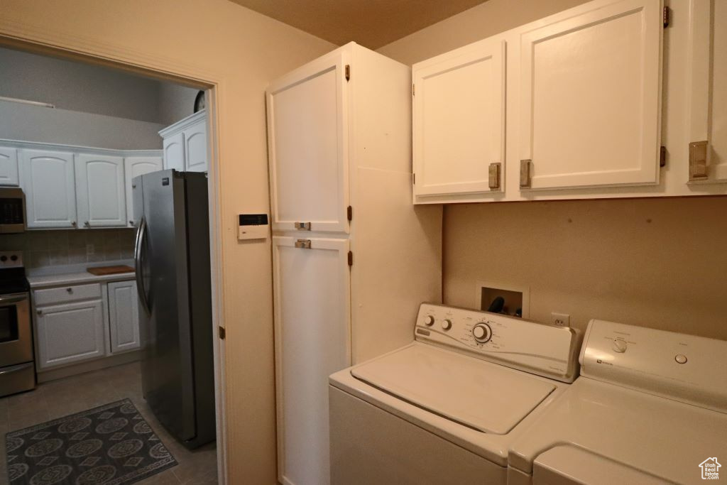 Washroom featuring washer hookup, cabinets, washing machine and dryer, and dark tile floors