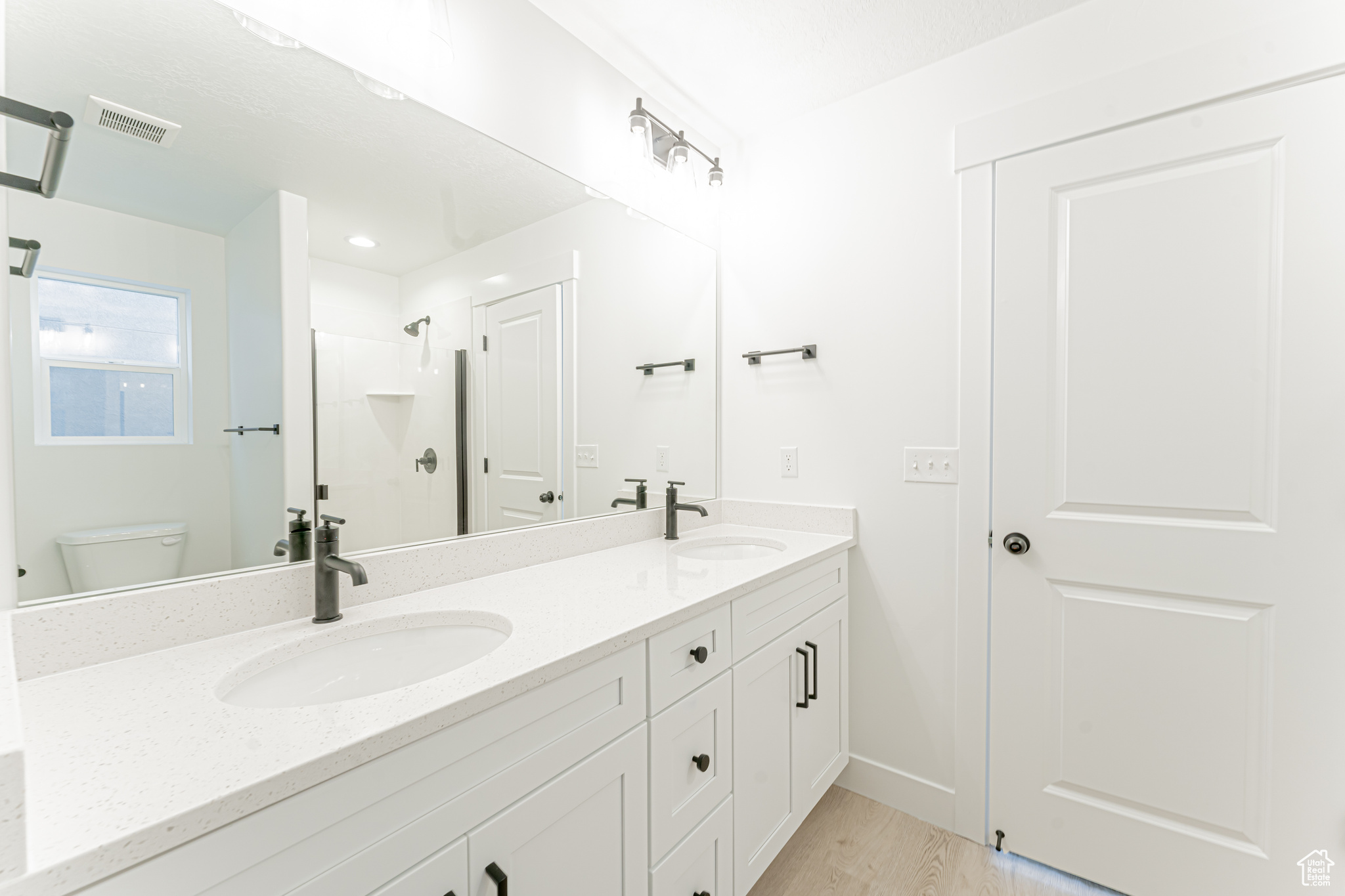 Bathroom with wood-type flooring, vanity with extensive cabinet space, toilet, and dual sinks