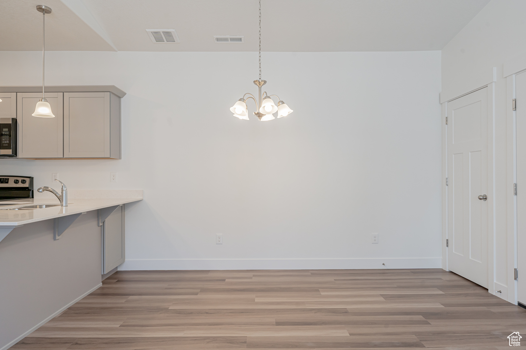 Unfurnished dining area featuring light hardwood / wood-style floors, sink, and a notable chandelier